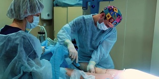 手术室:抽脂手术准备。一组外科医生给一个女孩做抽脂手术。外科医生的工作就像插管。