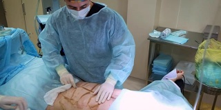 医生给一个男人做抽脂手术。收集套管的脂肪。为男人做整容手术，改善他的身体。