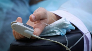病人的手在床上与血氧计。抢救病人，在手术中测量脉搏和血压。视频素材模板下载