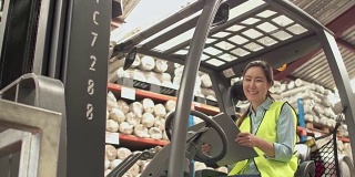 亚洲妇女工人的肖像在仓库的叉车上写在剪贴板上