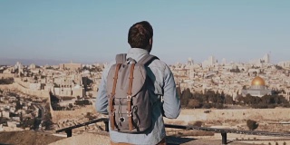 一名男子在以色列耶路撒冷用智能手机拍照。欧洲游客男欣赏古老的风景。旅行。慢动作