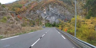 在法国，骑摩托车的人在风景山岩路上行驶。多雨的天气。第一个人的观点