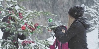 美丽的年轻女士在大雪中装饰圣诞树