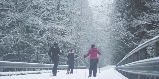 宽广的镜头三个年轻的女士一起远足在一个下雪的日子