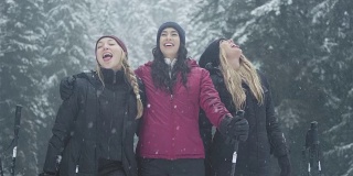 在一个下雪天，三位年轻的女士试图用她们的舌头捕捉雪，并对着镜头微笑