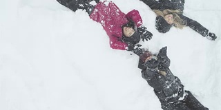 三个年轻漂亮的女人躺在地板上，向空中抛雪