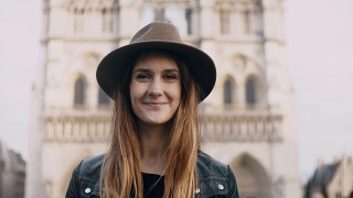 在巴黎圣母院附近的年轻美丽的女人戴着帽子的肖像，法国。女性看着镜头微笑视频素材模板下载