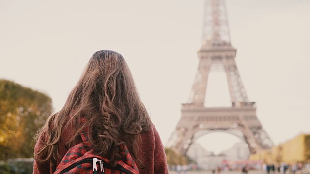 年轻的黑发女性用智能手机拍摄埃菲尔铁塔的背影。少年探索巴黎，法国