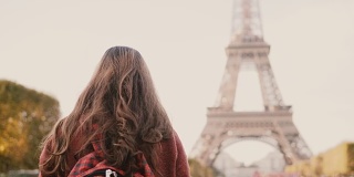 年轻的黑发女性用智能手机拍摄埃菲尔铁塔的背影。少年探索巴黎，法国