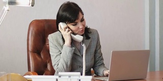 一位中年女性在办公室接听一个电话。