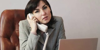 一位黑发的女商人正在一间光线明亮的现代办公室里通过电话进行谈判。