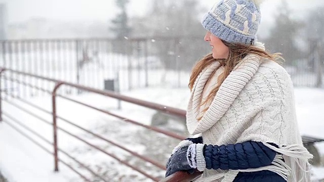 年轻美丽的女性站在和享受暴风雪在寒冷的冬日。