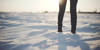 近距离的女人的脚走在雪沙漠在日落。Stabiblized慢动作镜头