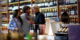 一对情侣在一家葡萄酒商店微笑着向酒庄老板询问葡萄酒的属性