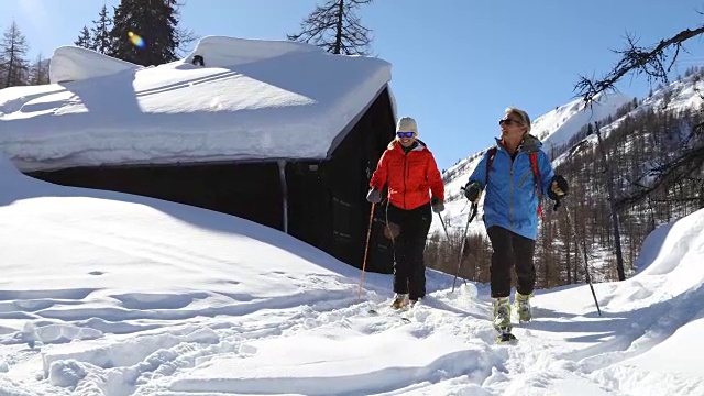 成熟的边远地区滑雪夫妇从山上小屋探索瑞士阿尔卑斯山