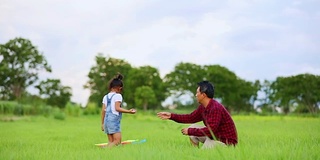 亚洲的小女孩和父亲带着风筝在夏季的草地上奔跑和快乐的大自然中，慢镜头