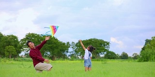 亚洲的小女孩和父亲带着风筝在夏季的草地上奔跑和快乐的大自然中，慢镜头