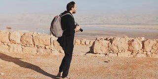 一个背着背包的人走在沙漠的山顶上。偶然的记者博客拍摄死海风景照片。以色列4 k