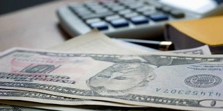 钱掉在办公室的桌子上。美元钞票和计算器。金融和储蓄的概念。