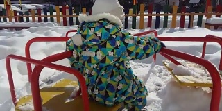 儿童游乐场有跷跷板，滑块，木梯，旋转木马。冬天废弃的操场下着雪，在公园里慢慢地下雪。