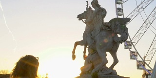 女游客拍照的马雕像和大轮，日落