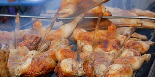 把整只鸡串在木棍上，放在烤架上烤制。街头食品泰国