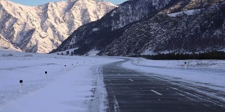 冬季飘雪的阿尔泰公路，在Chemal地区，以积雪覆盖的山脉为背景