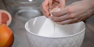 女性双手打破鸡蛋，将蛋黄从蛋白中分离出来。
