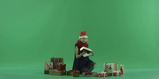 可爱的小女孩在圣诞帽得到了一个漂亮的圣诞礼物，色度键的背景