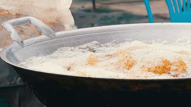 泰国和亚洲的街头小吃。女人在大锅里手工煮鸡肉，然后放上鸡块。在大炖锅中裹上面包屑的鸡肉煮沸