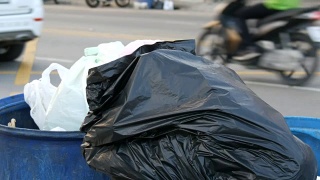 那个女人扔了一个塑料瓶。满垃圾桶的大垃圾袋装满了剩菜和垃圾在街上视频素材模板下载