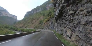 在法国，骑摩托车的人在风景山岩路上行驶。多雨的天气。第一个人的观点