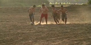 乡村的孩子们在阳光明媚的日子里踢足球。