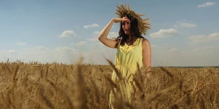 戴着麦冠、穿着黄衣服的女人凝视着远方。田野上夏日的天空