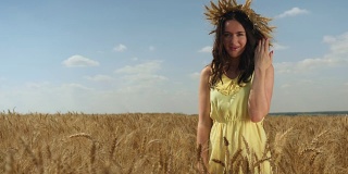 麦冠黄裙的女子抬头望着镜头。田野和蓝天