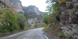 在法国，骑摩托车的人在风景山岩路上行驶。多雨的天气。第一个人的观点