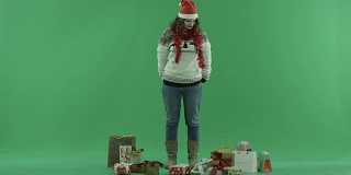 美丽的年轻女子在圣诞帽与圣诞礼物，色度键的背景