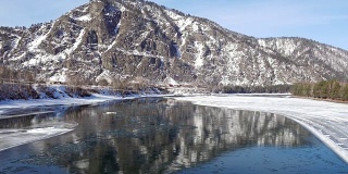冬季鸟瞰阿尔泰河卡顿，背景为水中浮冰和群山