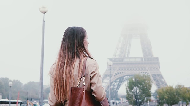 年轻时尚的女人走在巴黎市中心的背影，在法国的清晨浓雾和看埃菲尔铁塔