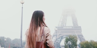 年轻时尚的女人走在巴黎市中心的背影，在法国的清晨浓雾和看埃菲尔铁塔