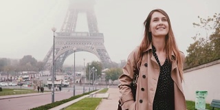年轻快乐的女人走在法国巴黎埃菲尔铁塔附近。游客微笑着环顾四周。慢动作