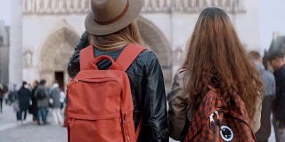 两个旅行的女人背着背包走在巴黎圣母院附近，著名的大教堂，法国巴黎
