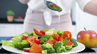适当的营养，把橄榄油倒在蔬菜上，厨房里的新鲜有机沙拉视频素材模板下载