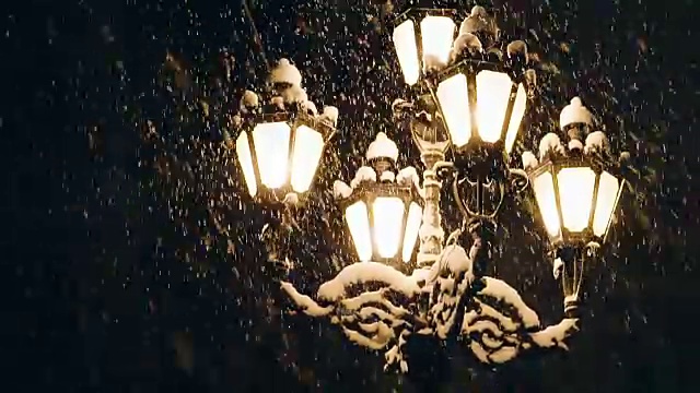 夜冬路灯和飘落的雪花。灯在晚上。街灯以飘落的雪为背景。
