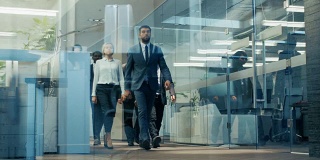 商务人士/律师代表团自信地走过公司大楼走廊的低角度镜头。多元文化的商人和女商人在行动。