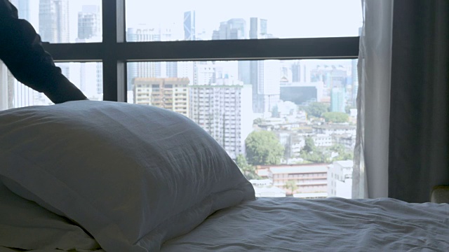 在床上拨弄枕头的人从卧室可以看到城市的景色