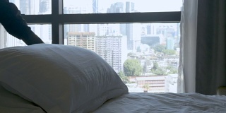 在床上拨弄枕头的人从卧室可以看到城市的景色