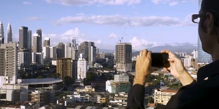 游客用手机拍摄双塔的城市照片
