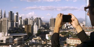 从一个用智能手机拍摄现代城市的男性游客身上挤出来