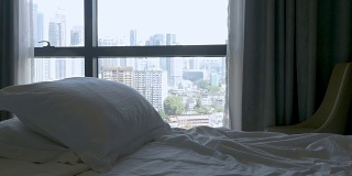 抬起一张空床，上面有两个枕头，可以看到大城市的景色